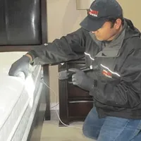 Bed bug inspection technician checking a mattress and bed frame for signs of infestation in Tuscaloosa, AL