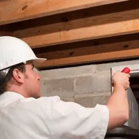 Termite inspection technician checking a basement wall and framing for termite activity in Tuscaloosa, AL